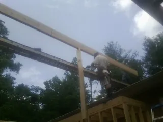 Carpenter setting a ridge beam over a new addition frame — Ice Dam Removal by Roofing Brothers in Deferiet