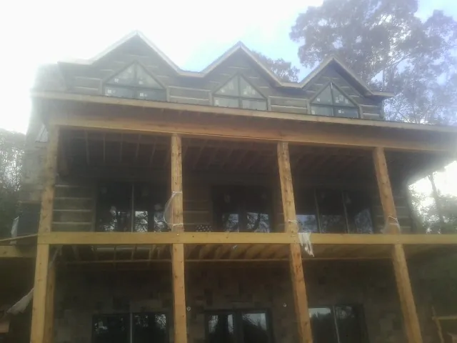 Dormers and porch framing on a large log home under construction — Roof Coating work by our crew in Deferiet