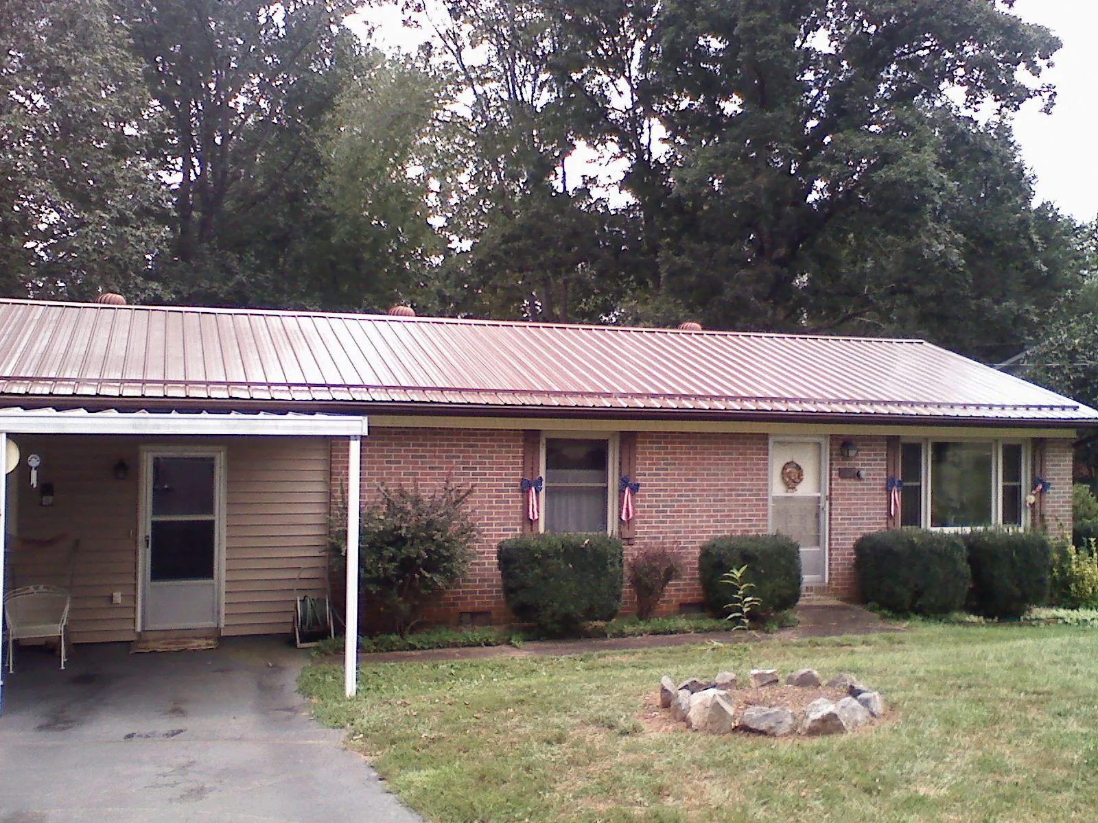 Bronze metal roof and carport on a brick ranch home — Roof Repair work by our crew in Deferiet