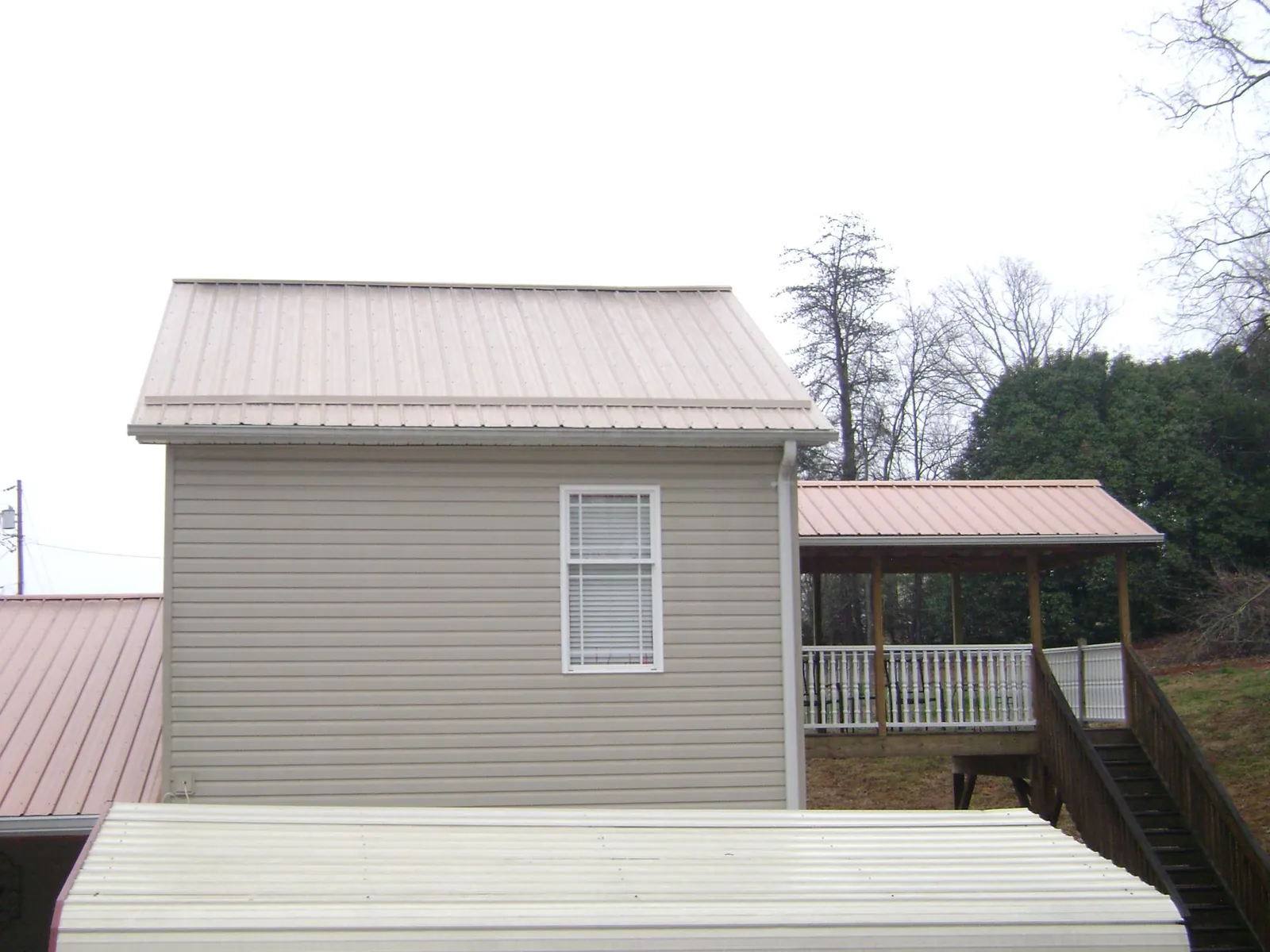Tan metal roofs on a two story addition and attached porch, from a Roof Replacement job in Deferiet