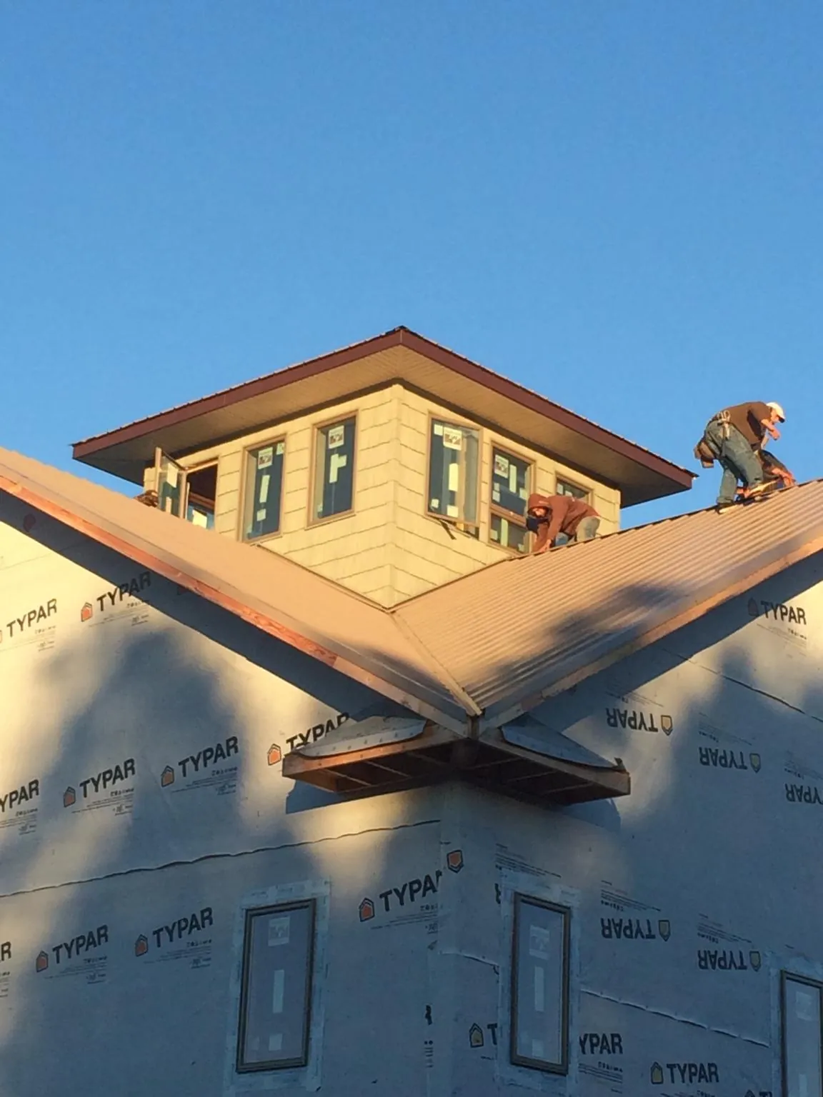 Roofers working around a rooftop cupola on a new metal roof at sunset — Roof Waterproofing in Deferiet by Roofing Brothers